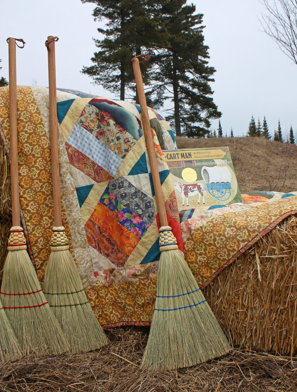 traditional handmade broomcorn children's broom resting on straw bales and a quilt